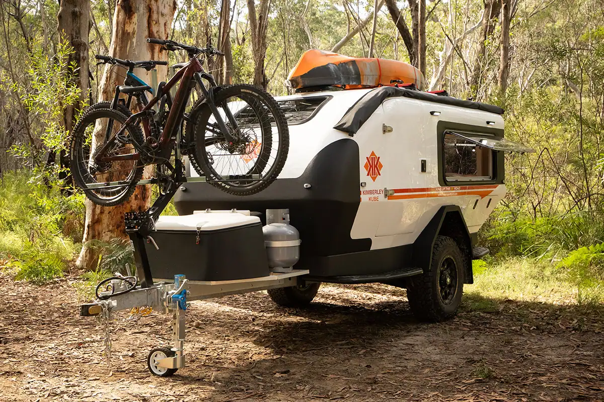 Kube Teardrop Camper with iSi Bicycle Rack Australian Bush Teardrop camper with iSi bicycle rack attached, parked outdoors with Australian bush background. Passenger side view.