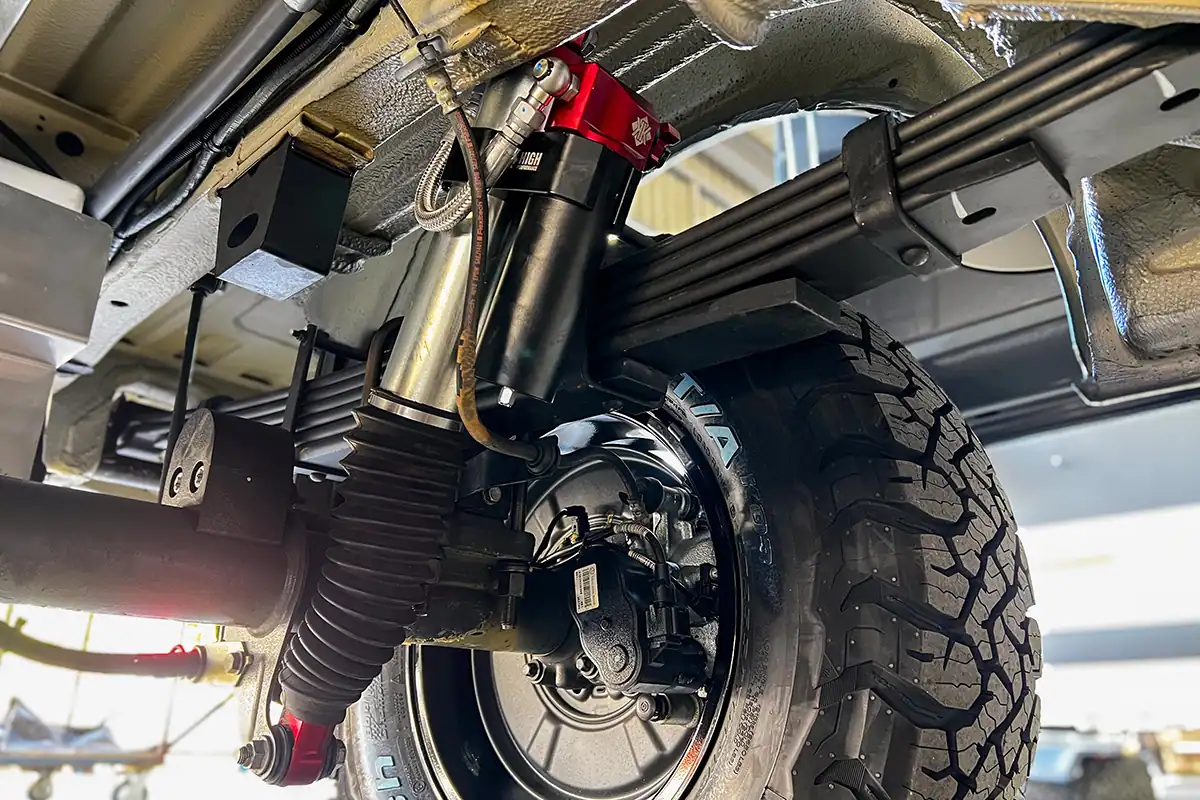 Kimberley Kampers Off Road Motorhome Suspension Close-up of Kimberley Kampers off-road motorhome suspension with heavy-duty shock absorber and rugged tire, designed for durability and performance in remote Australian terrains.